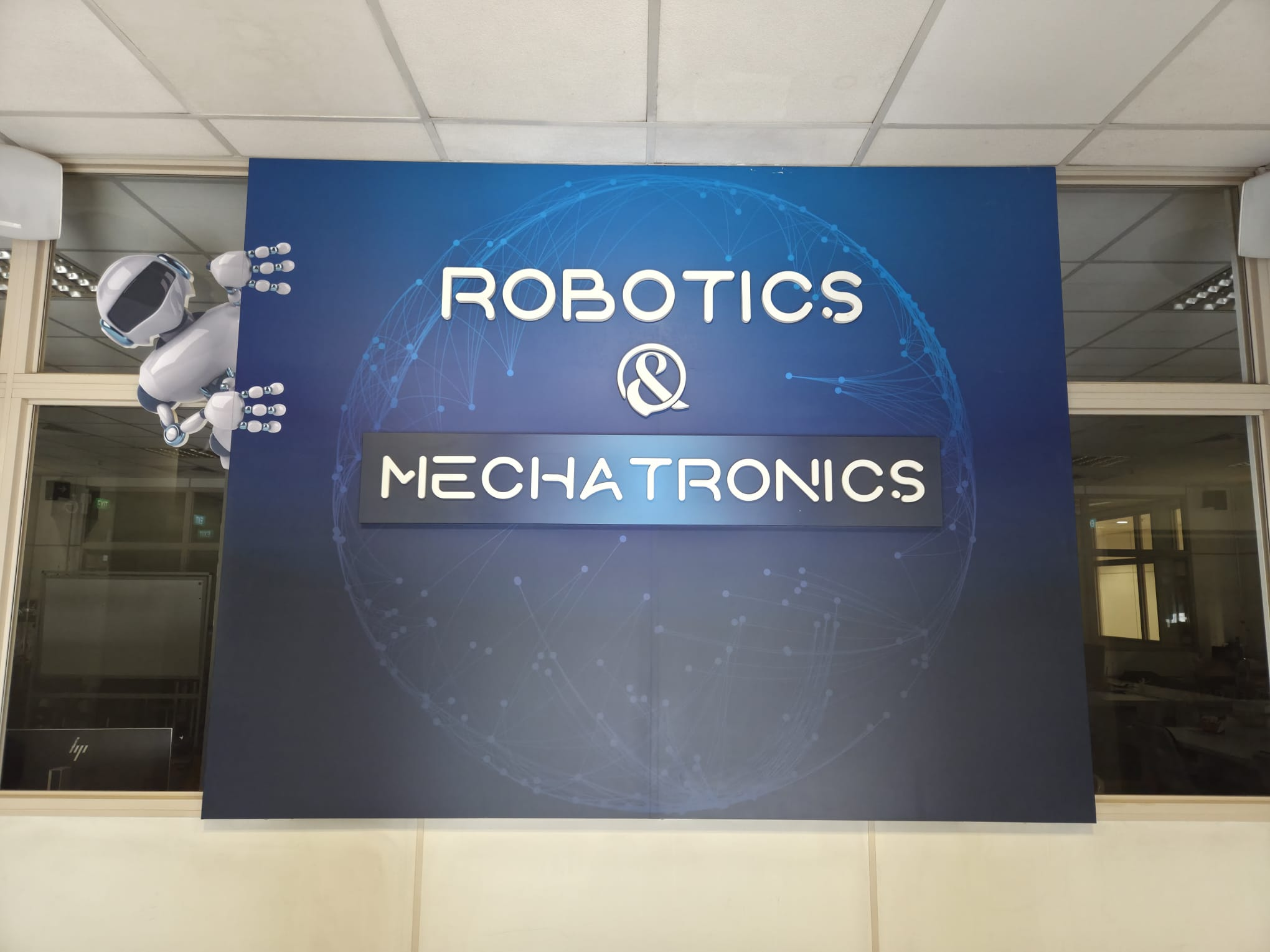 Sign reading ROBOTICS & MECHANICS with a small robot model next to it.